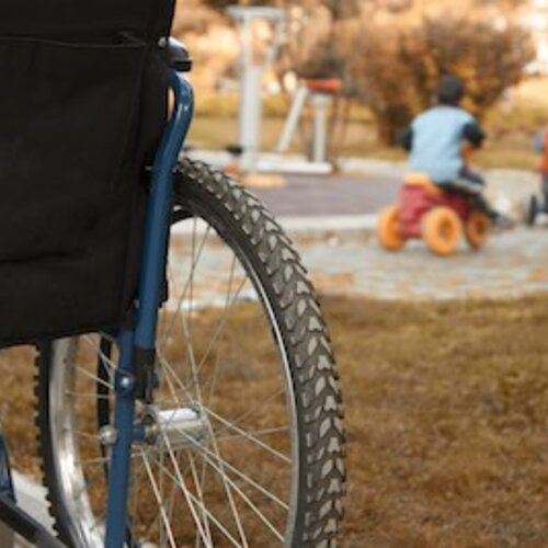 Foto van een achterwiel van een rolstoel bij een speeltuin