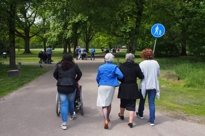 Foto van wandelaars met senioren en persoon on rolstoel in park Tilburg