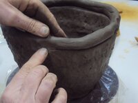 Foto van twee handen die werken aan keramiek