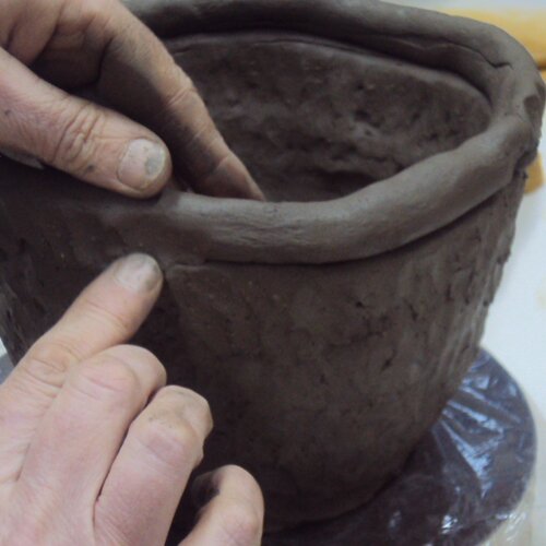 Foto van twee handen die werken aan keramiek