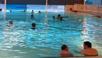 Foto van een zwembad en mensen die aan het zwemmen zijn