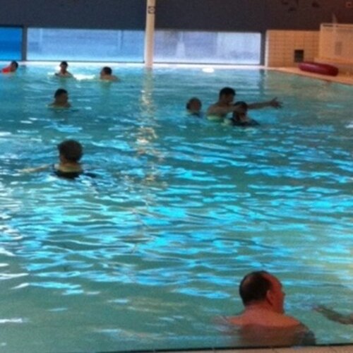 Foto van een zwembad en mensen die aan het zwemmen zijn