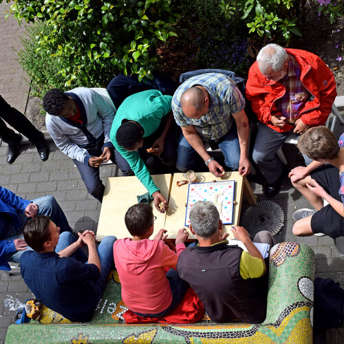 Foto van groepje mensen aan een tuintafel met elkaar in gesprek