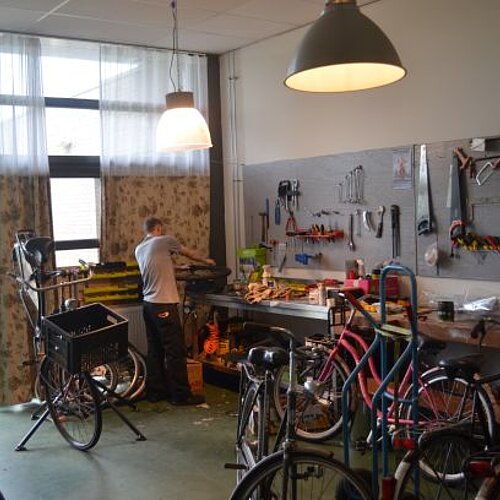 Foto van een man die een fiets repareert