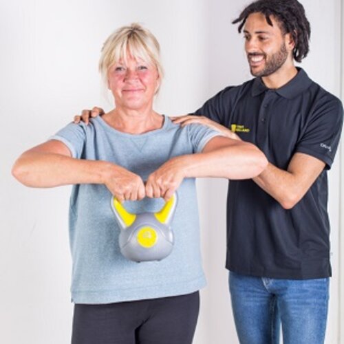 Foto van een fysiotherapeut en een client die een kettlebell vasthoud