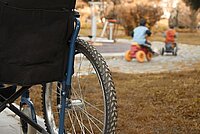 Foto van een achterwiel van een rolstoel bij een speeltuin