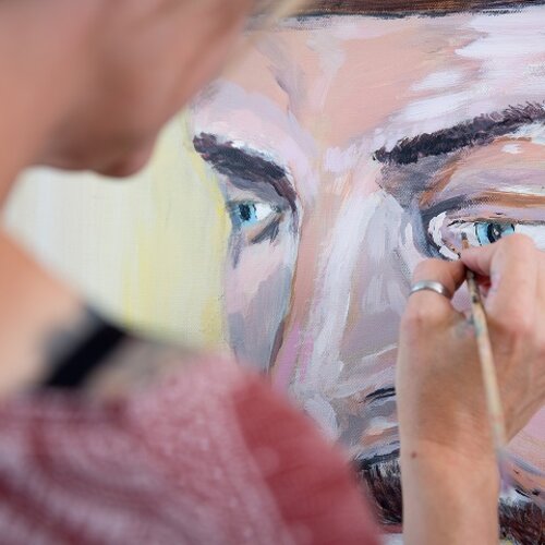 Foto van een persoon die een abstract gezicht schildert