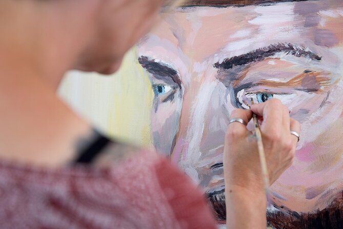 Foto van een persoon die een abstract gezicht schildert
