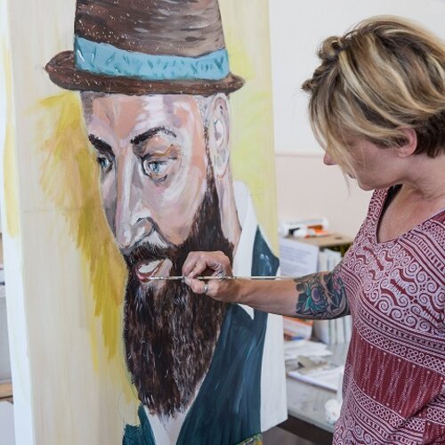 Een vrouw werkt aan een schilderij op een schildersezel