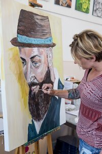 Een vrouw werkt aan een schilderij op een schildersezel