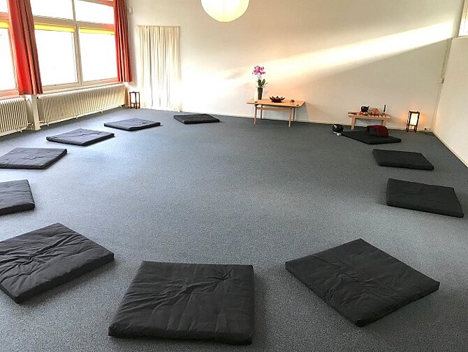 Foto van een praktijkruimte met matjes in een cirkel op de vloer