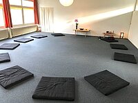 Foto van een praktijkruimte met matjes in een cirkel op de vloer