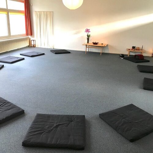 Foto van een praktijkruimte met matjes in een cirkel op de vloer