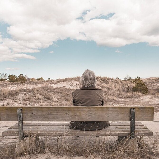 Foto van vrouw alleen op bankje in de duinen