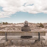 Foto van vrouw alleen op bankje in de duinen